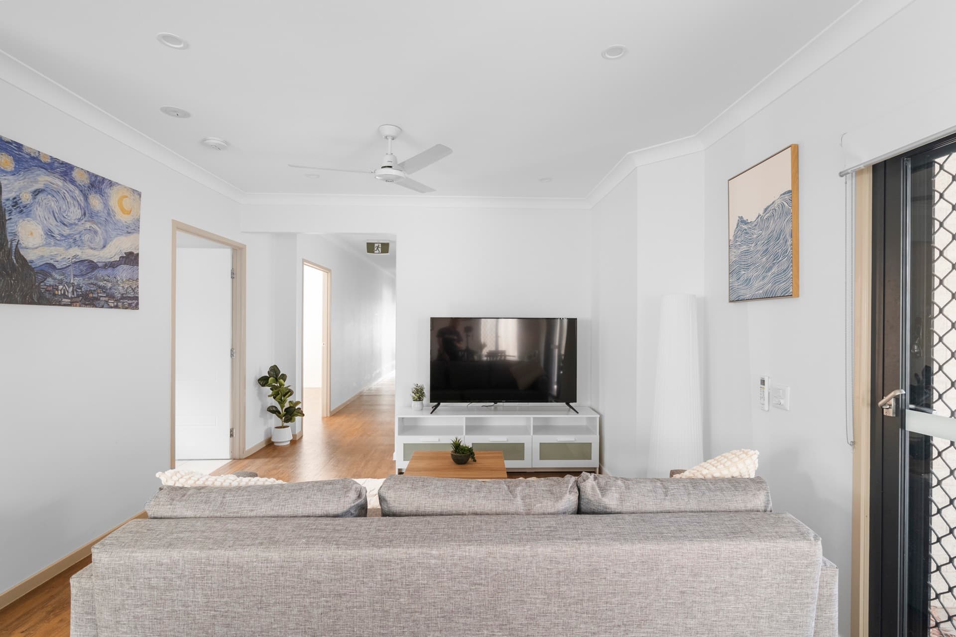 Living room with grey sofa, Van Gogh Starry Night print on the wall, and white TV unit with glass doors